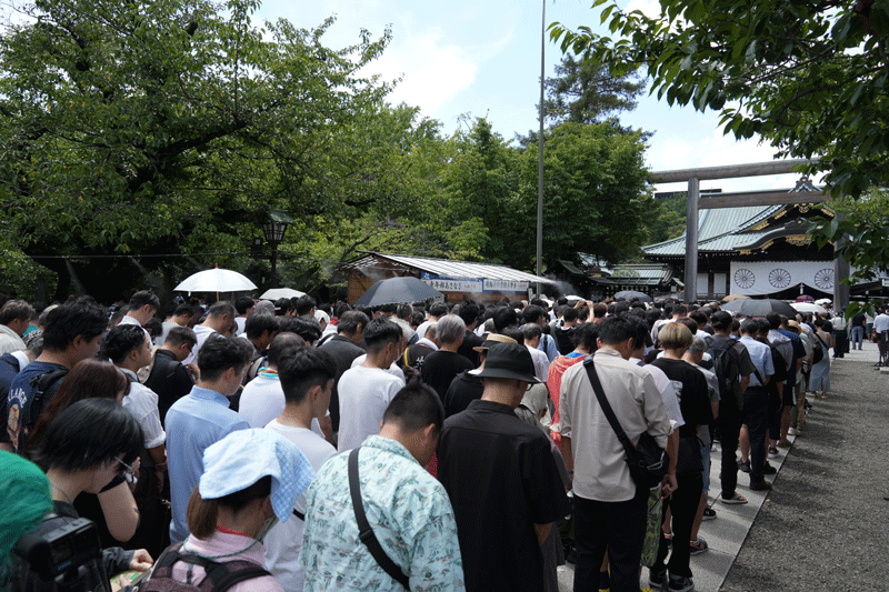 正午ごろの靖國神社境内。時報に合はせ黙祷する参拝者